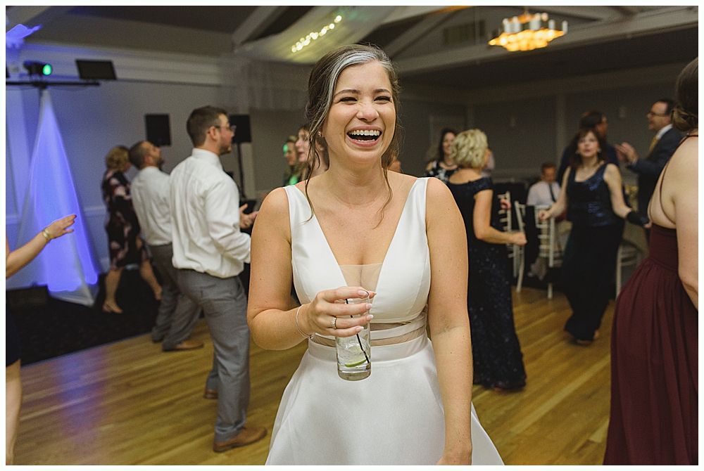 Man in suit laughing with mouth wide open at an event.