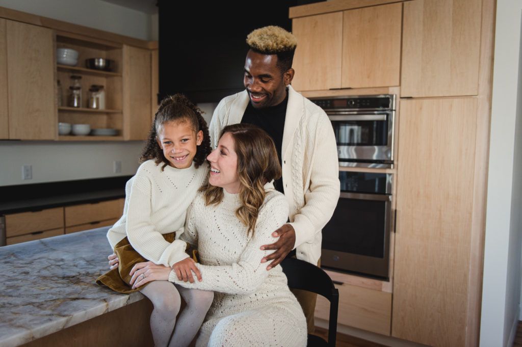 Family in matching sweaters smiles in a modern kitchen.