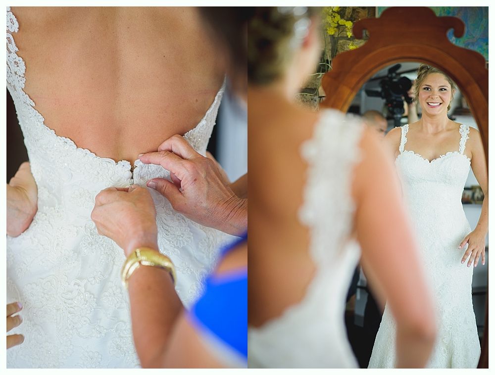 Bride with arms up, making a funny face, groom looking at his hand, cake cutting in background.