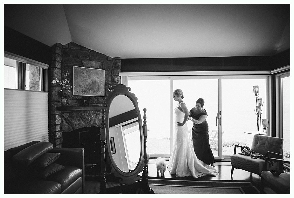 Bride with arms up, making a funny face, groom looking at his hand, cake cutting in background.