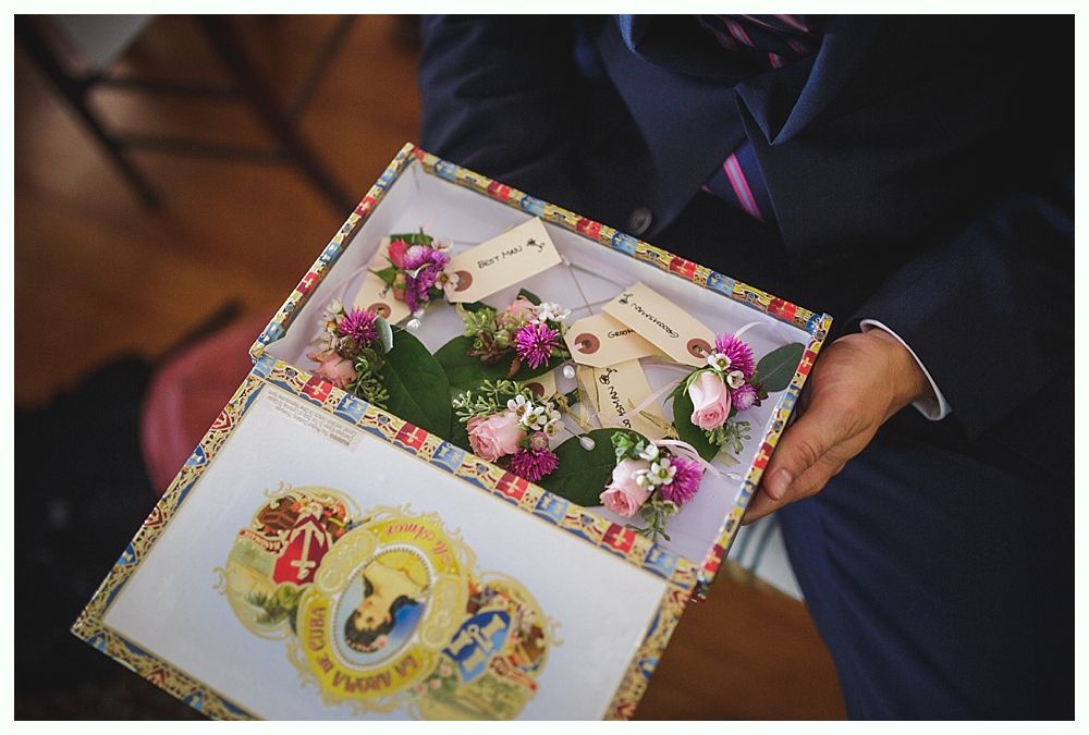 Bride with arms up, making a funny face, groom looking at his hand, cake cutting in background.