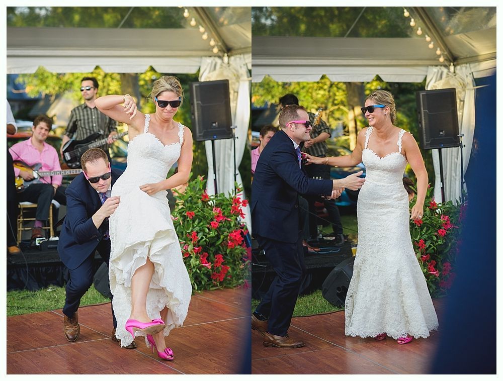 Bride with arms up, making a funny face, groom looking at his hand, cake cutting in background.