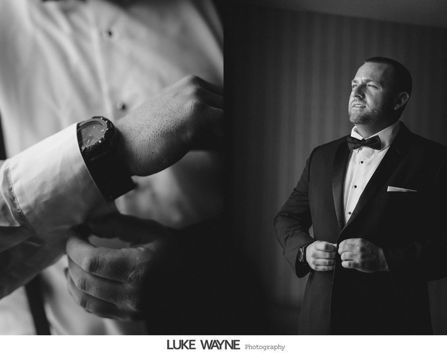 Man adjusting cufflinks and wearing a tuxedo with a bow tie. Black and white.