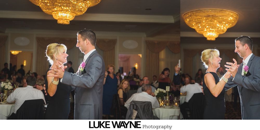 A man and woman dance at a wedding reception beneath a large chandelier.