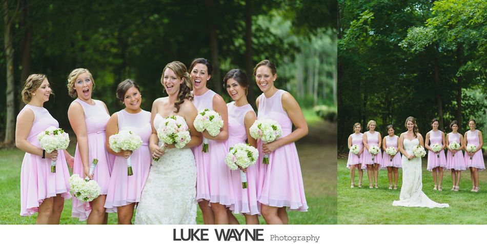 Bride and bridesmaids in pink dresses pose with bouquets. Outdoor wedding scene.