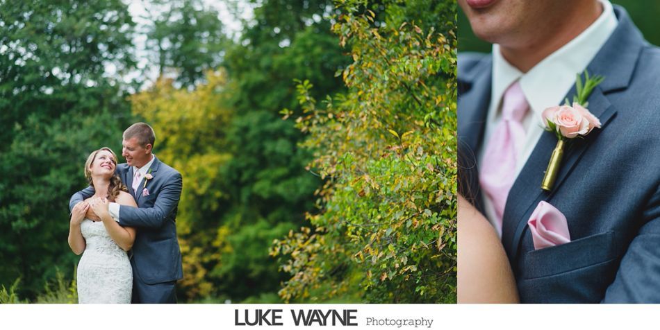 Couple embracing outdoors; bride in white dress, groom in blue suit with pink tie, and flowers.