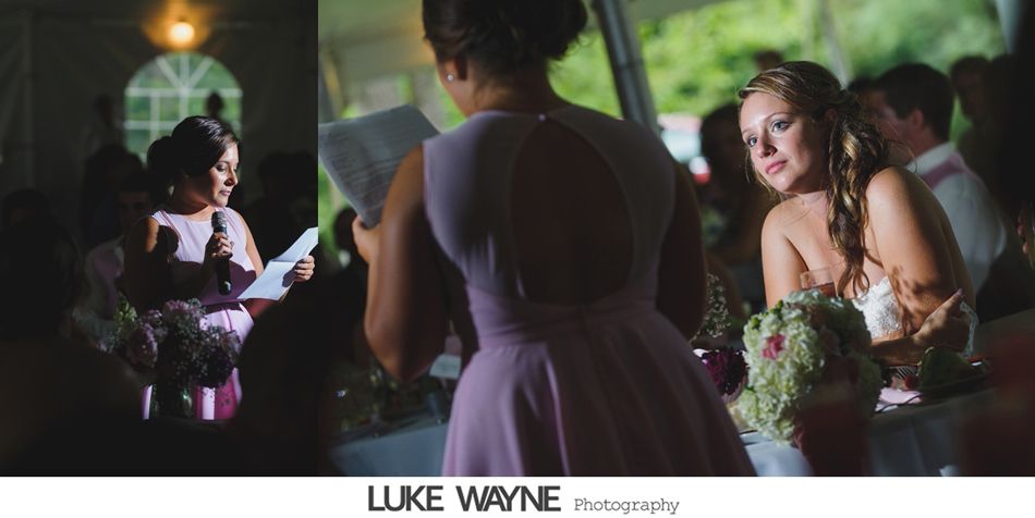 Woman in lavender dress gives a speech at a wedding, bride looks on.
