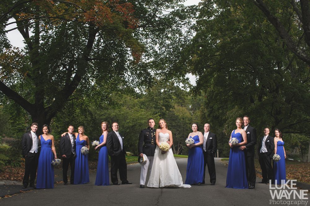 Wedding party on steps, bride in white dress, bridesmaids in purple dresses, groomsmen in gray suits.
