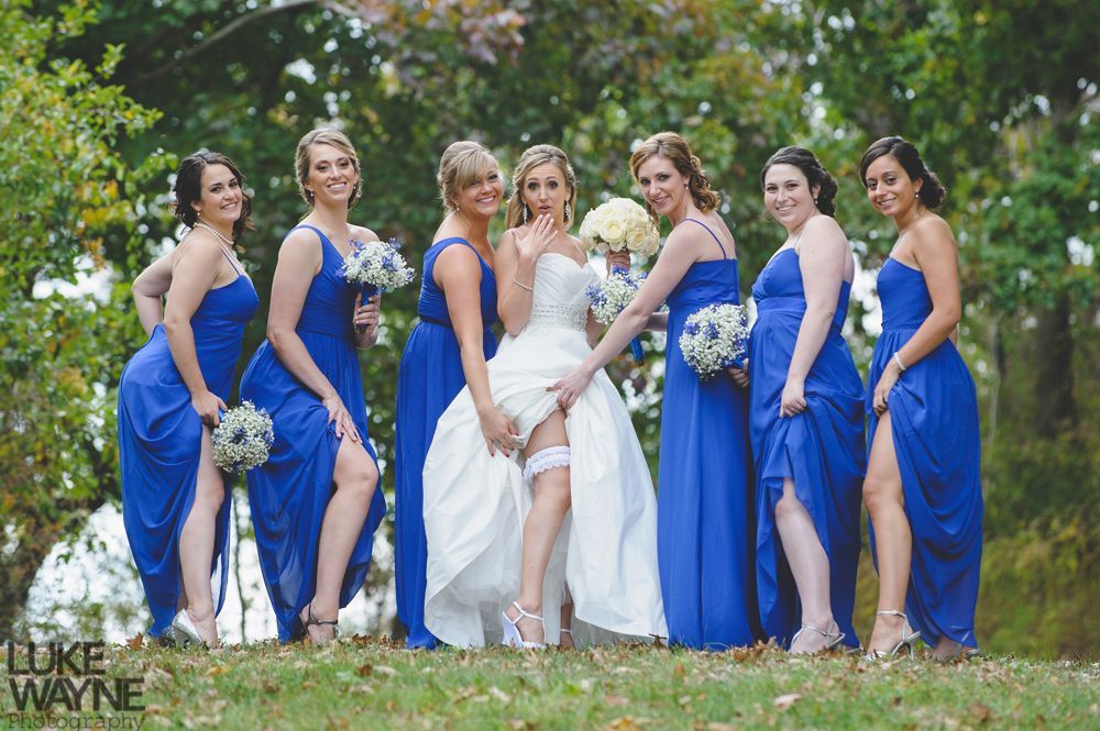 Bride in white dress laughs with bridesmaids in purple gowns.