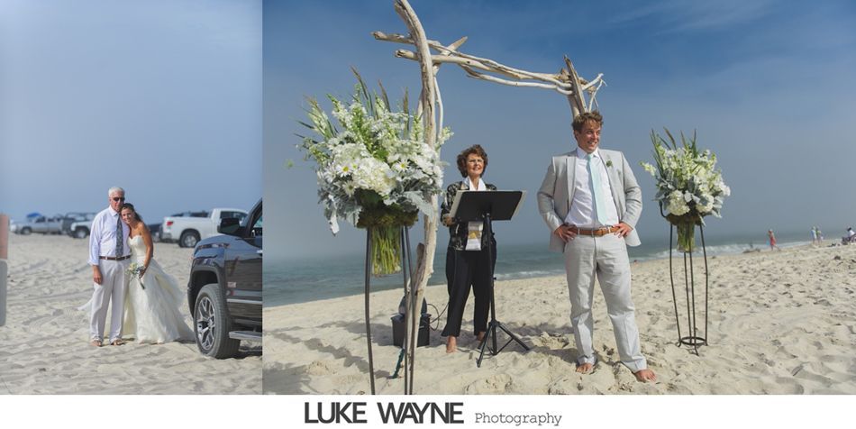 Wedding ceremony on the beach: Bride with father, groom at altar, officiant, driftwood arch, flowers, sunny sky.