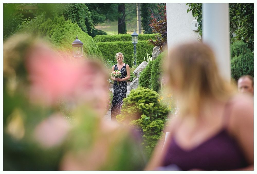 Bride with arms up, making a funny face, groom looking at his hand, cake cutting in background.