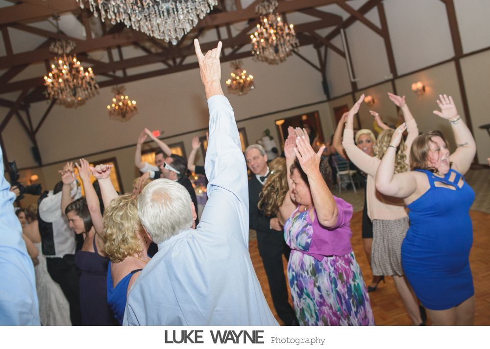 People dancing at a wedding reception, one person raises a 
