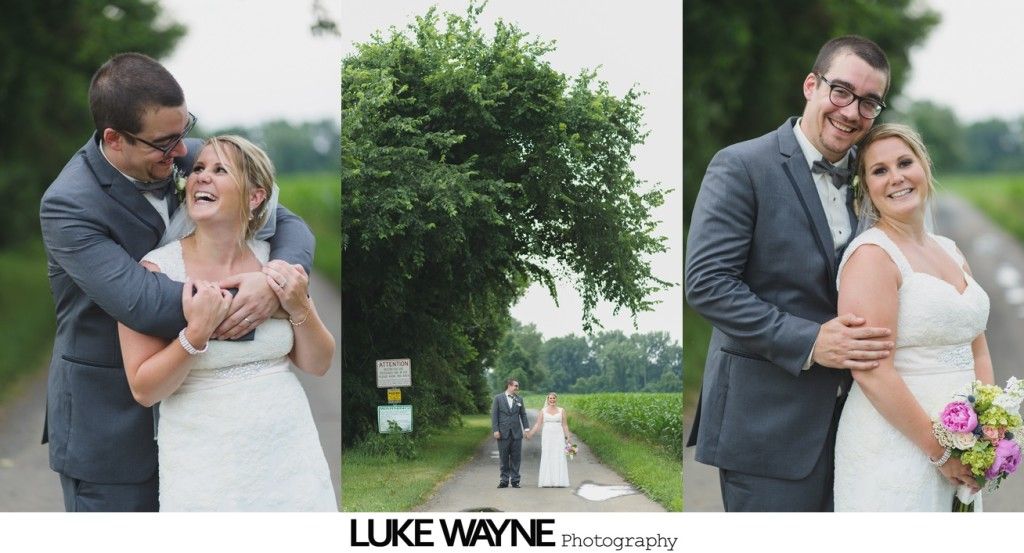 Bride and groom on a road. Man hugs woman, smiles, and holds flowers.