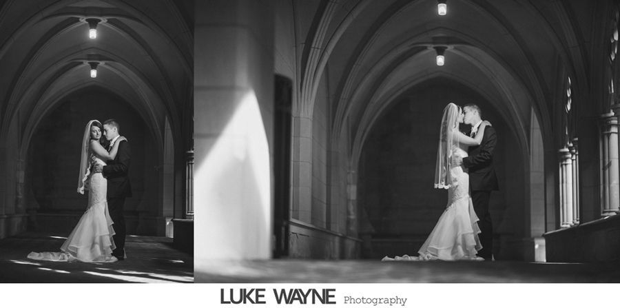 Bride and groom kissing in a vaulted corridor. Sunlight streams from the side. Black and white photo.