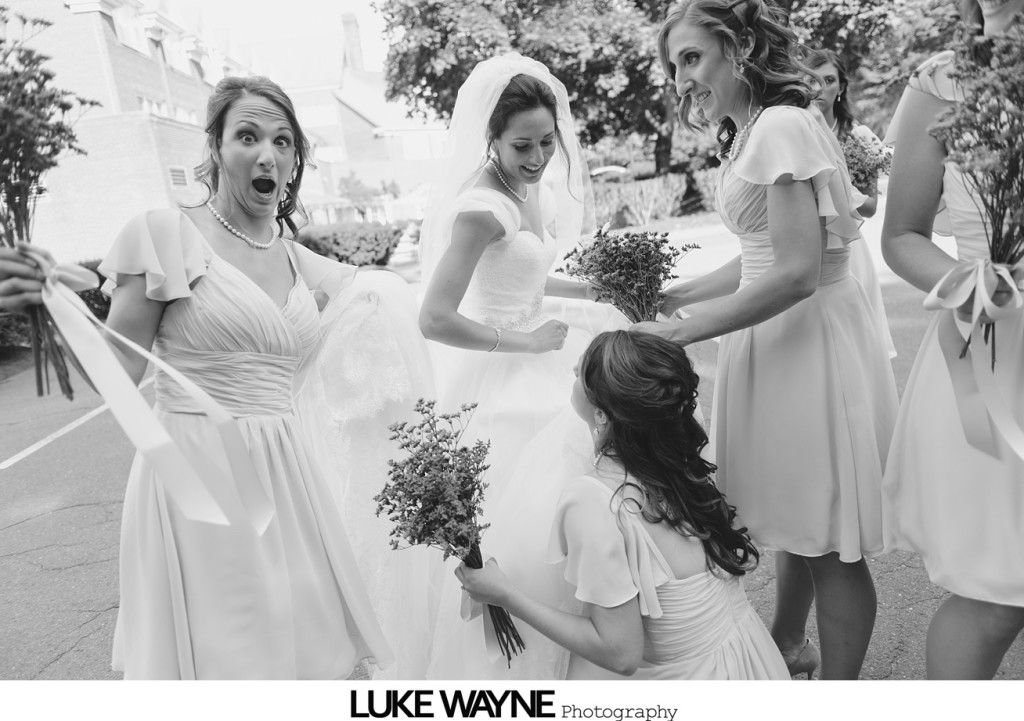 Bride surrounded by bridesmaids, one with smudged face, all holding bouquets outdoors.