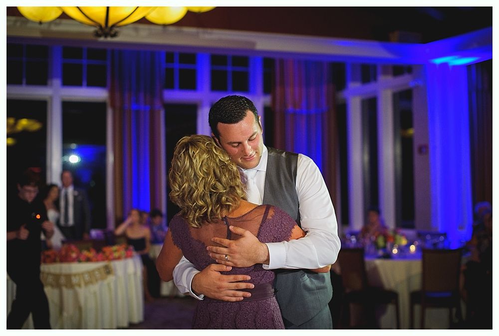 Man in vest and woman dancing closely at a wedding reception; blue and gold lighting.
