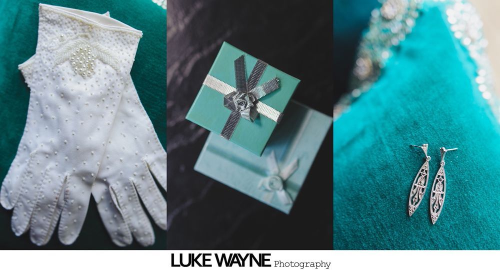 Wedding dress hanging, makeup supplies on table.