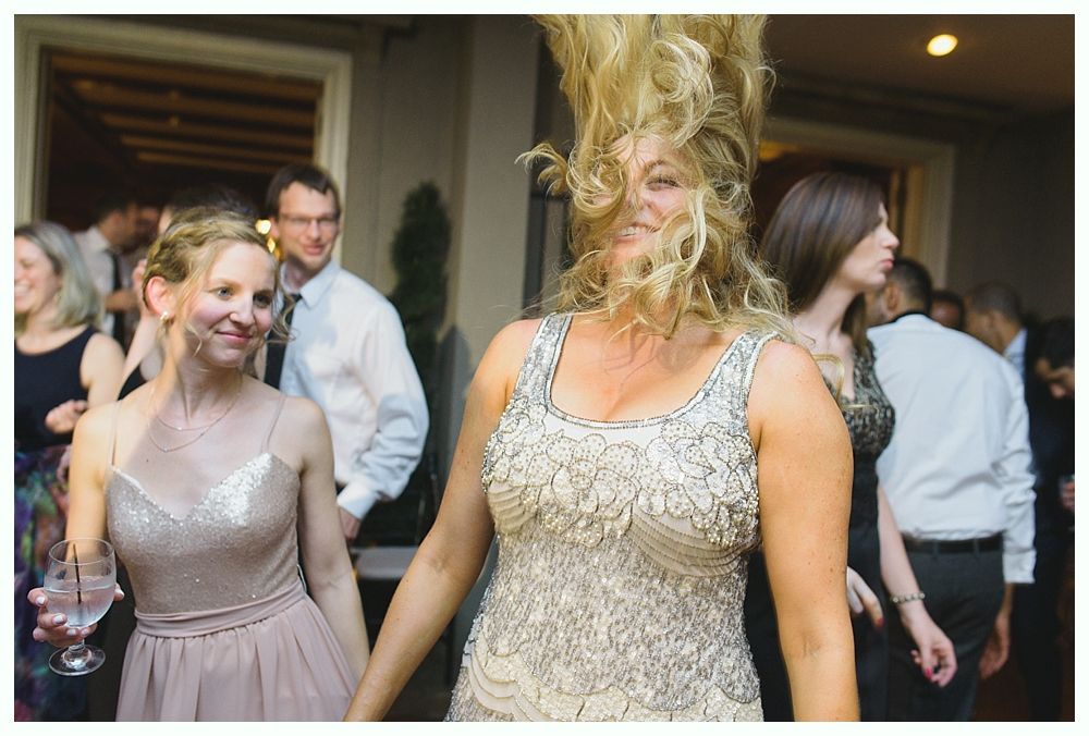 Two women dancing at a party; one with wild hair, wearing a beaded dress.