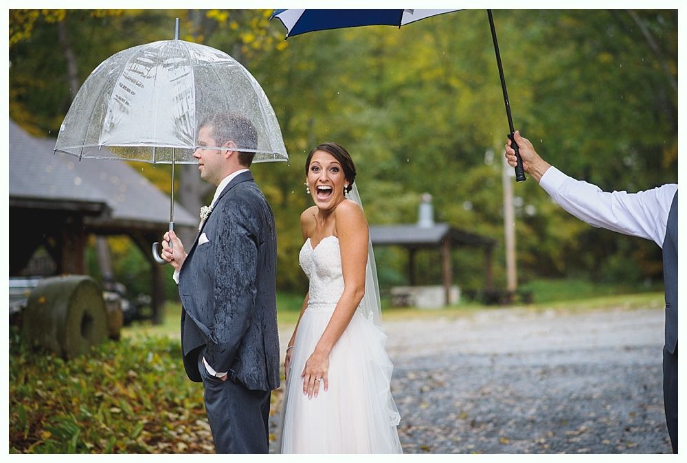 Bride and groom surprised by rain, under umbrellas, outdoors.