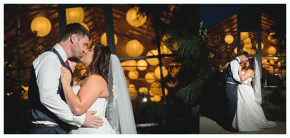 Newlyweds kiss under paper lanterns at night.