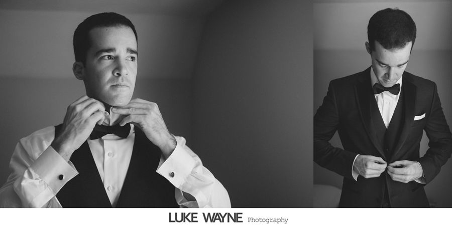 Man adjusts bowtie, then buttons suit jacket, in a black and white photo.