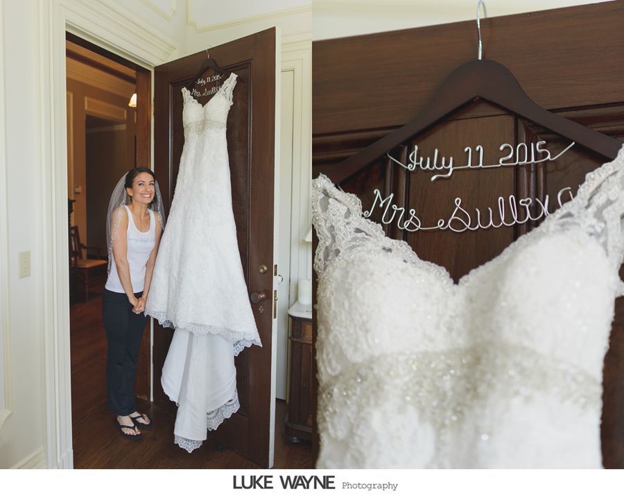 Woman looks at wedding dress hanging on a door, close-up of the dress on a personalized hanger.