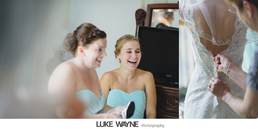 Bridesmaids laugh while bride gets dress buttoned on wedding day.