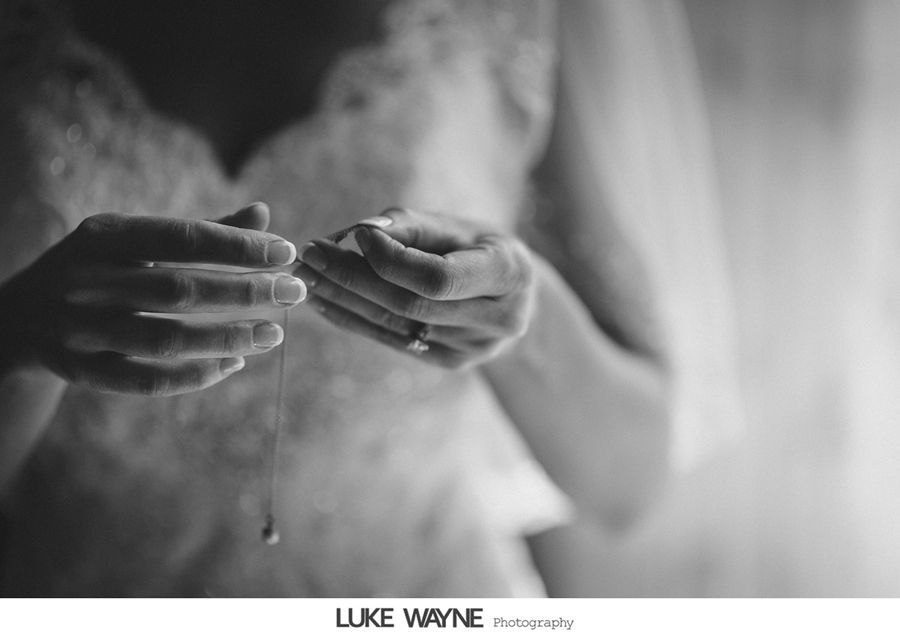 Bride holding a necklace, preparing for the wedding ceremony, black and white image.