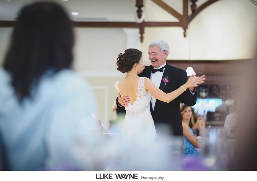 Bride dancing with father at wedding reception. Father smiles, wearing a tuxedo.