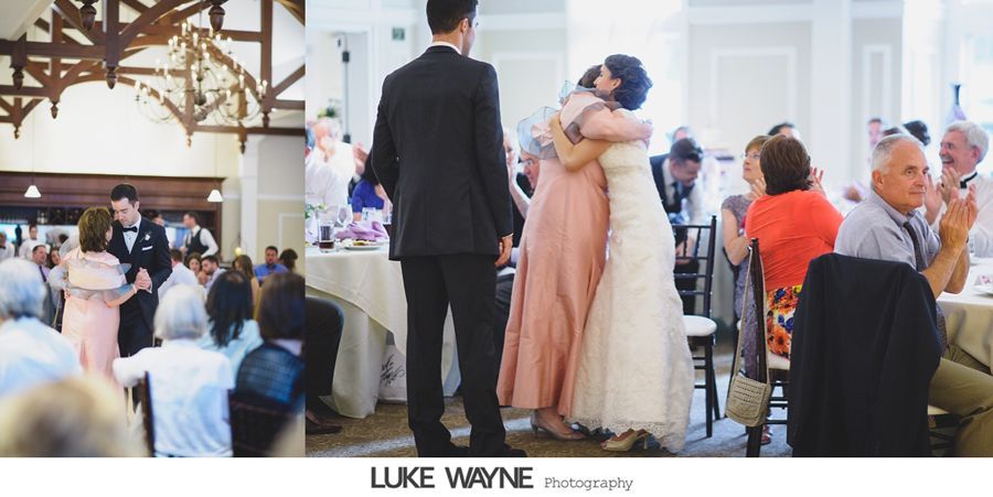 Bride hugs a woman in pink dress at a wedding reception; guests watch and clap.