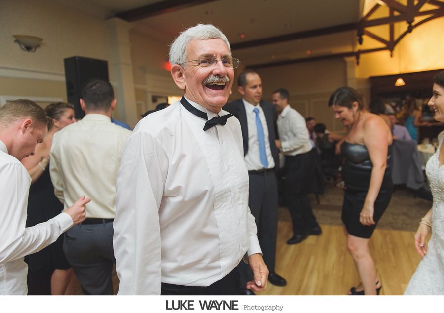 Smiling man with bow tie dancing at a wedding reception.