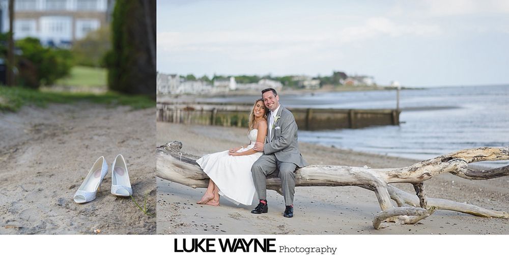 Bride and groom sitting on driftwood on a beach, woman's heels on the sand.