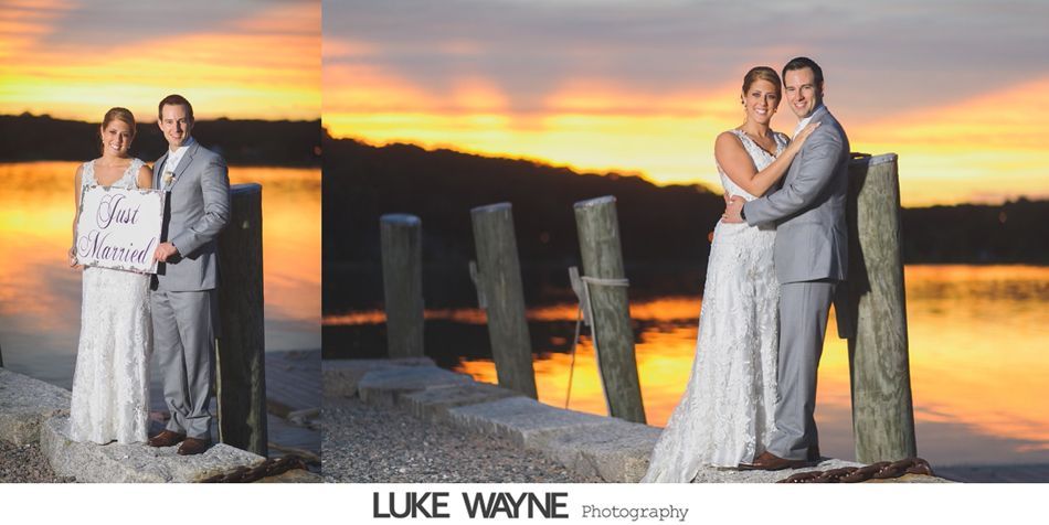 Newlyweds pose on a pier at sunset. Bride in a white dress, groom in a gray suit, embracing.