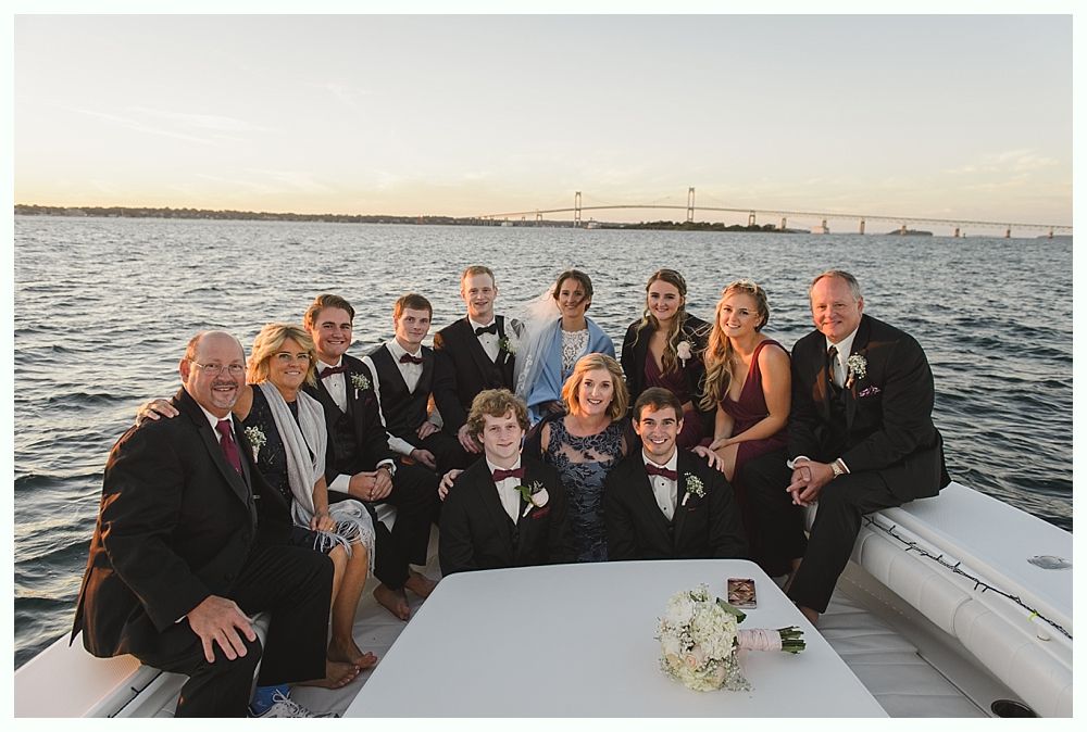 Family group on a boat, smiling, with a bridge in the background, likely a wedding photo.