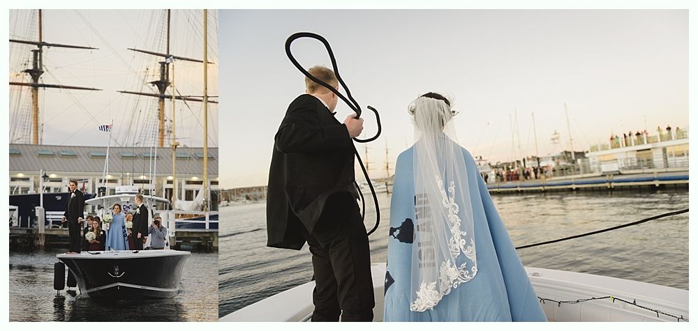 Wedding couple on boat, groom holding rope, bride in blue dress, water and pier visible.