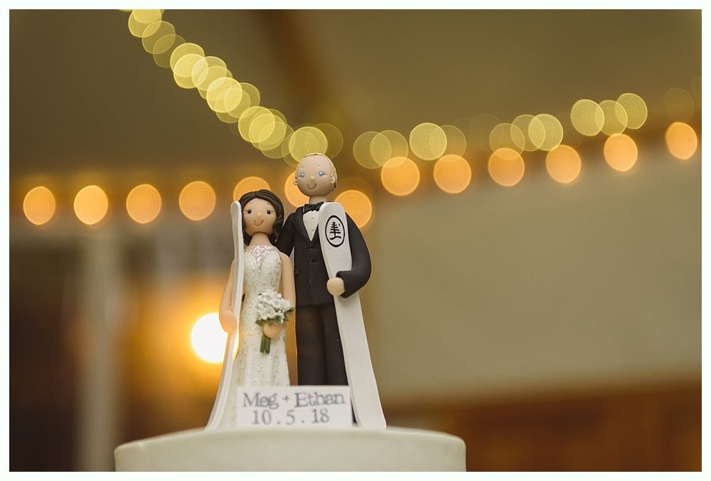 Wedding cake topper with bride, groom, and string lights. Text reads 