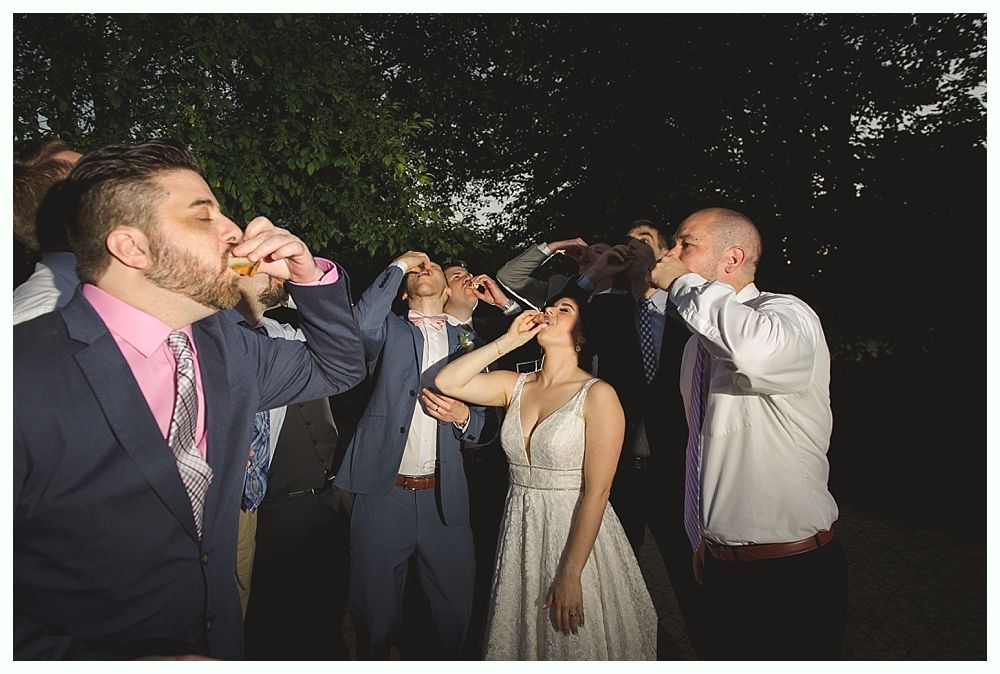 Group of people toasting and drinking shots outdoors at night.
