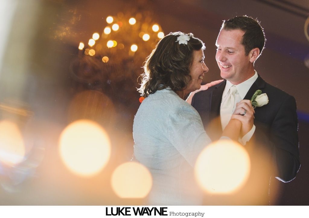 Couple dancing, smiling, with soft focus lights in background.