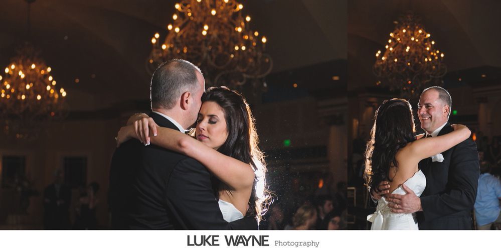 Bride and groom dance at reception, under ornate chandeliers.