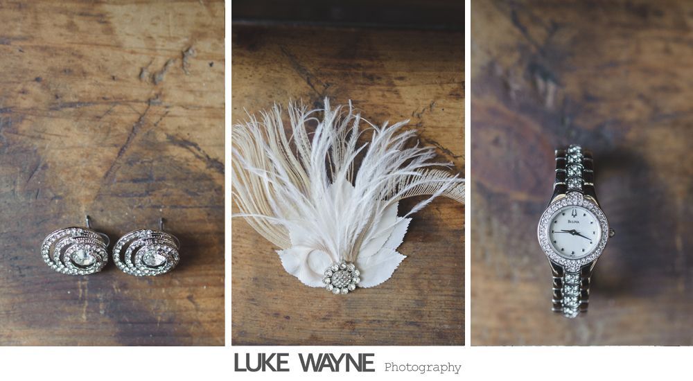 Jewelry arrangement: earrings, feather hair accessory, and a jeweled watch on a wooden surface.