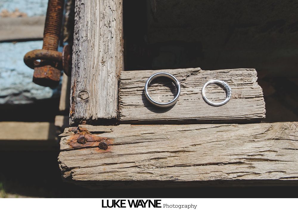 Wedding rings on weathered wooden plank, rustic setting.
