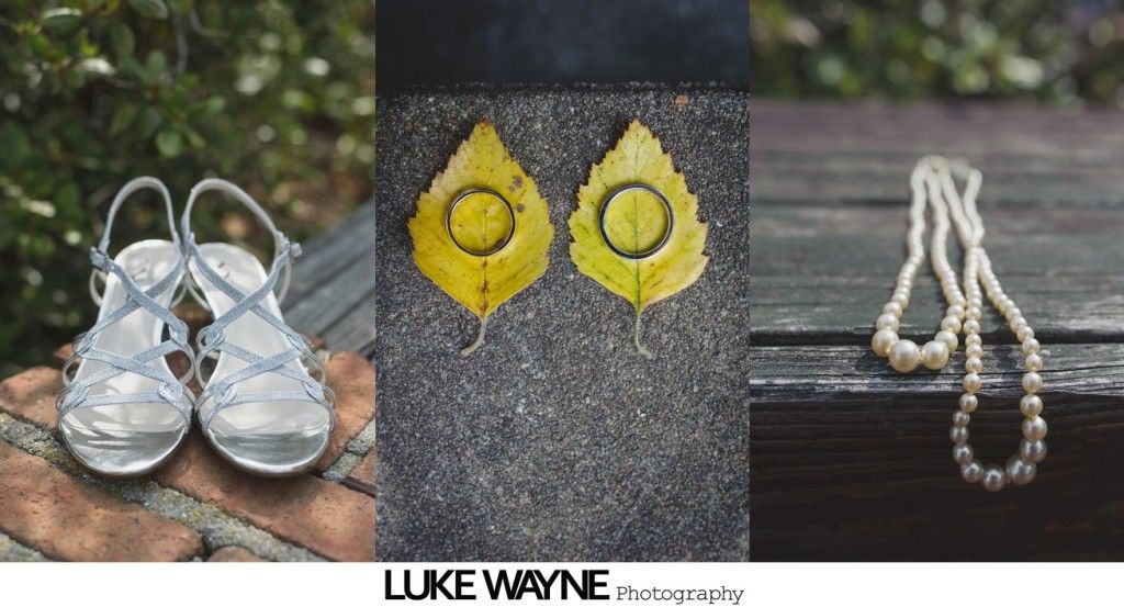Silver bridal sandals, two yellow leaves with circles, pearl necklace on wood.
