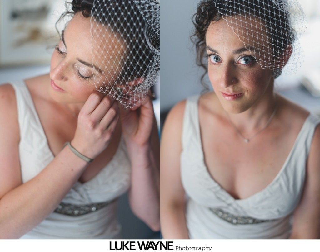 Bride adjusting earring, wearing veil and white dress, looking down and then at camera.