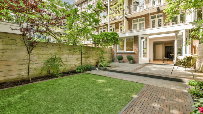 Courtyard garden with green lawn, stone path, and apartment balconies overlooking the space