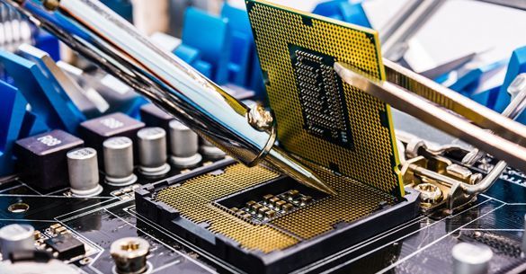 A close up of a computer processor being soldered on a motherboard.