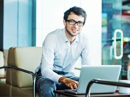 A man is sitting in a chair using a laptop computer.