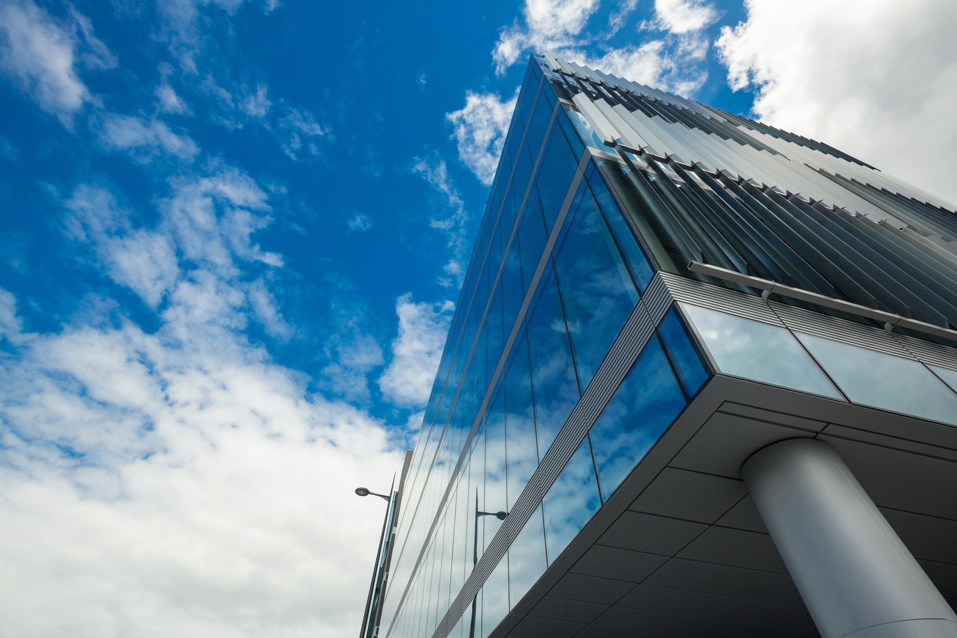 Modern glass building with reflective blue panels against a bright cloudy sky