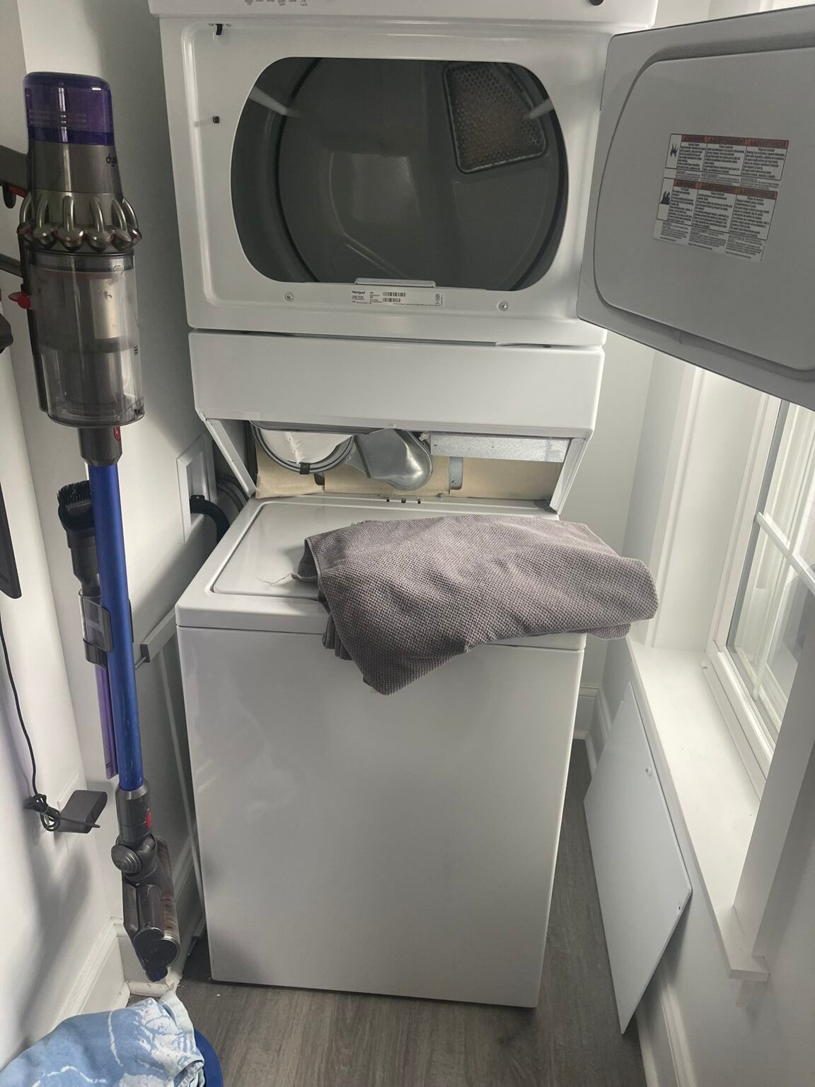 A washer and dryer are stacked on top of each other in a laundry room.