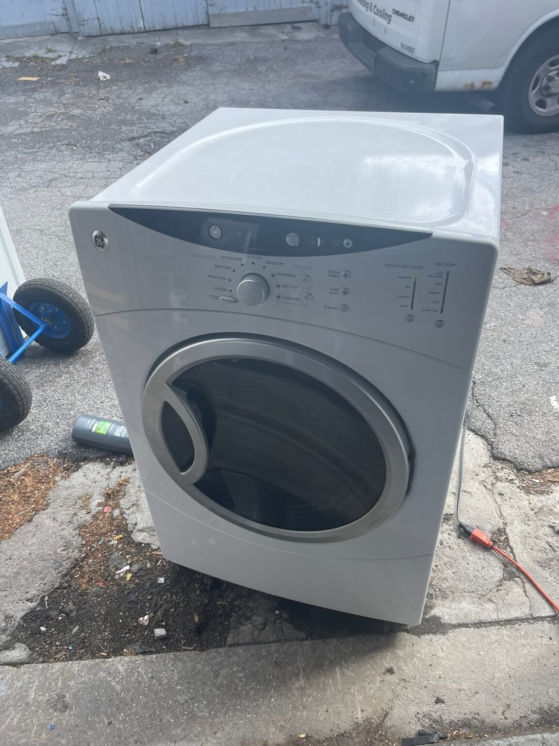 A white dryer is sitting on the side of the road.