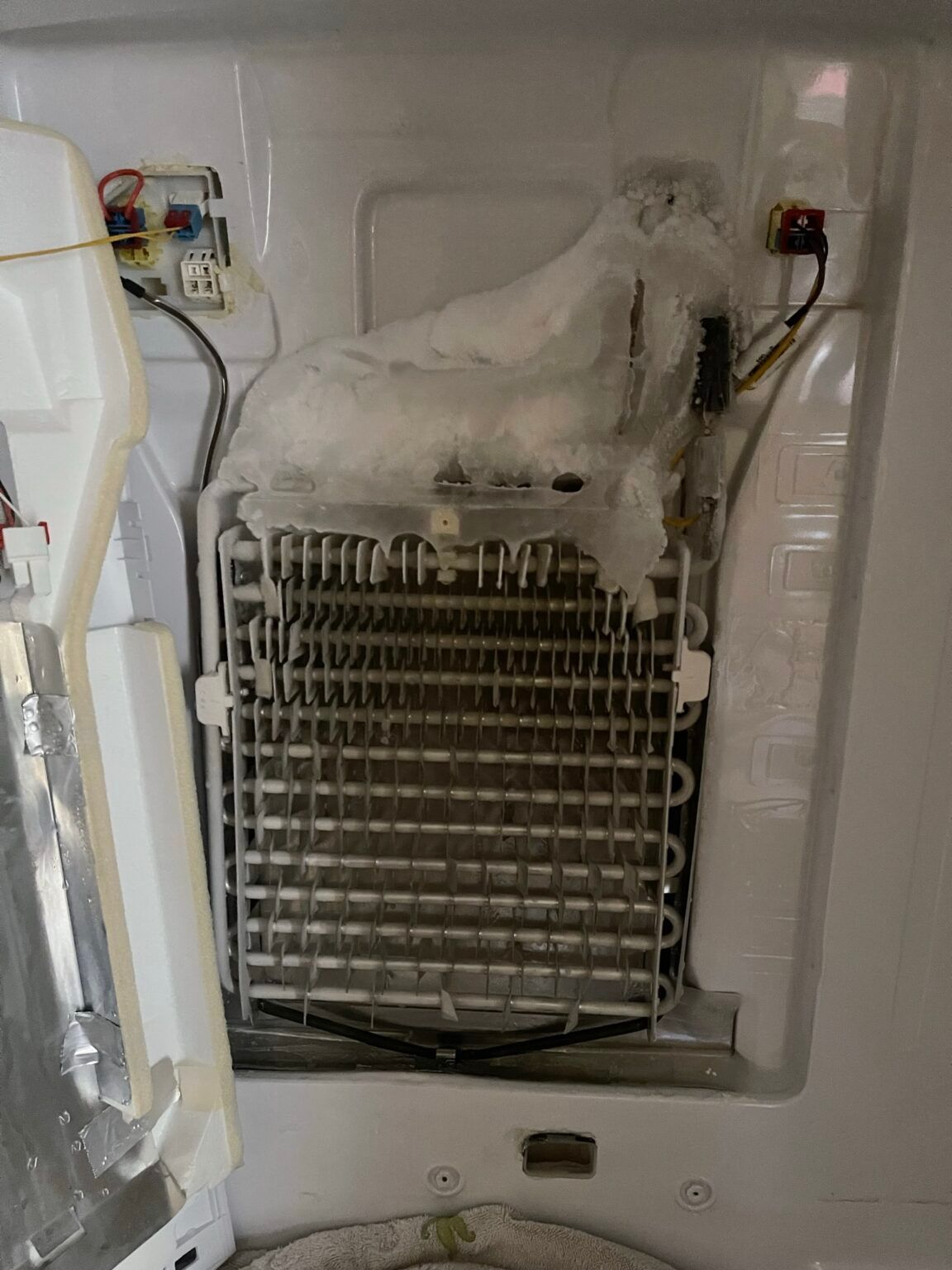 The inside of a refrigerator with a broken ice maker.